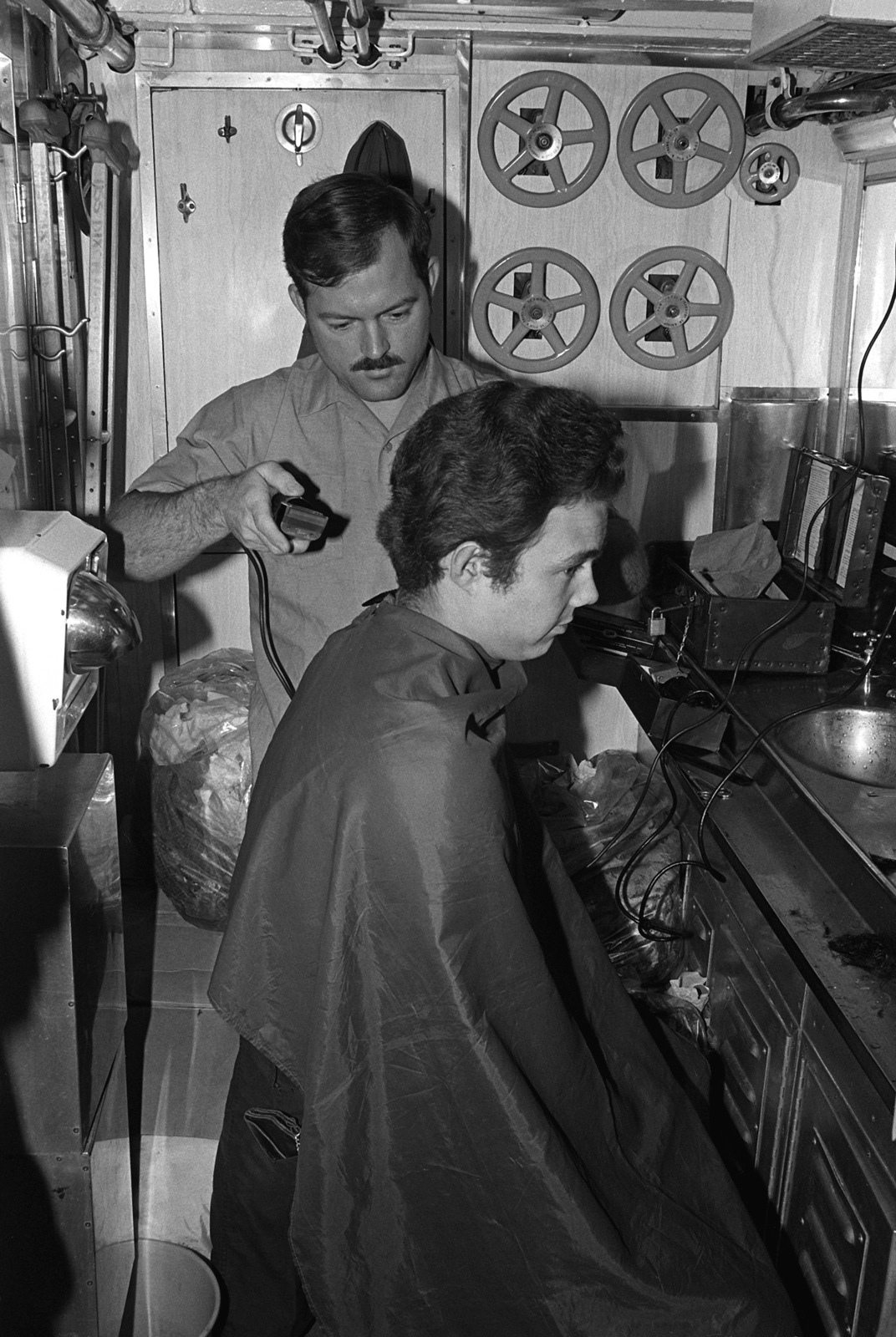 A crewman aboard the attack submarine USS BONEFISH (SS-582) gets a hair ...