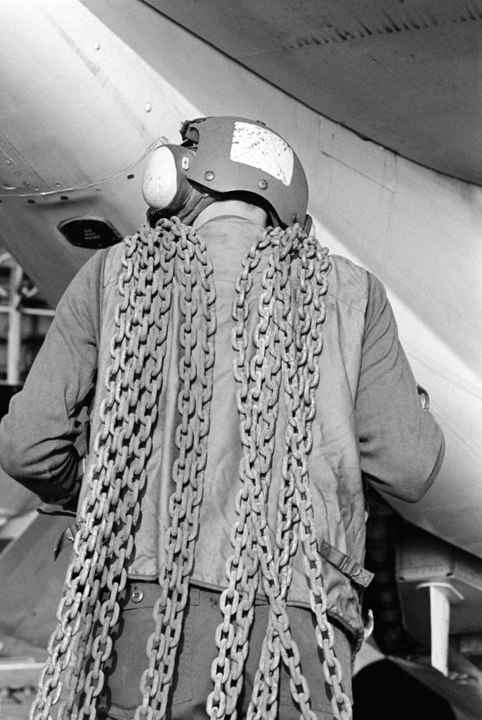 A Flight Deck Crewman Carries Tie Down Chains To Secure Aircraft Aboard The Aircraft Carrier Uss