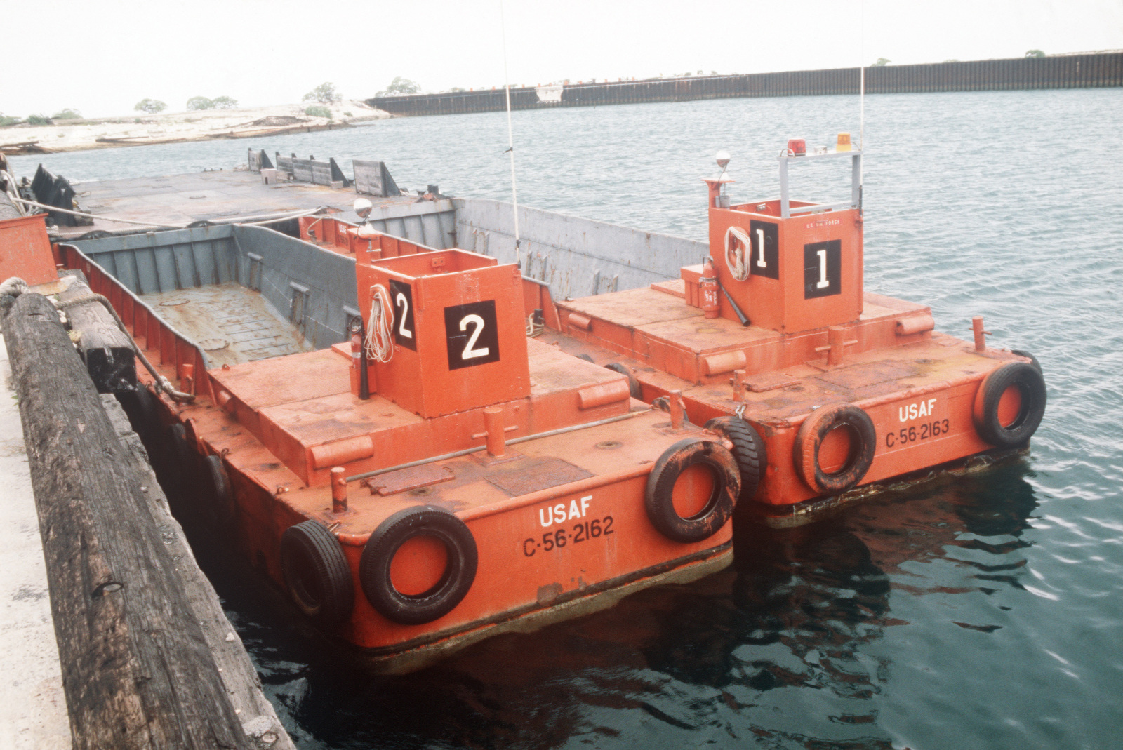 Two US Air Force LCM 6 landing craft docked at a pier - NARA & DVIDS
