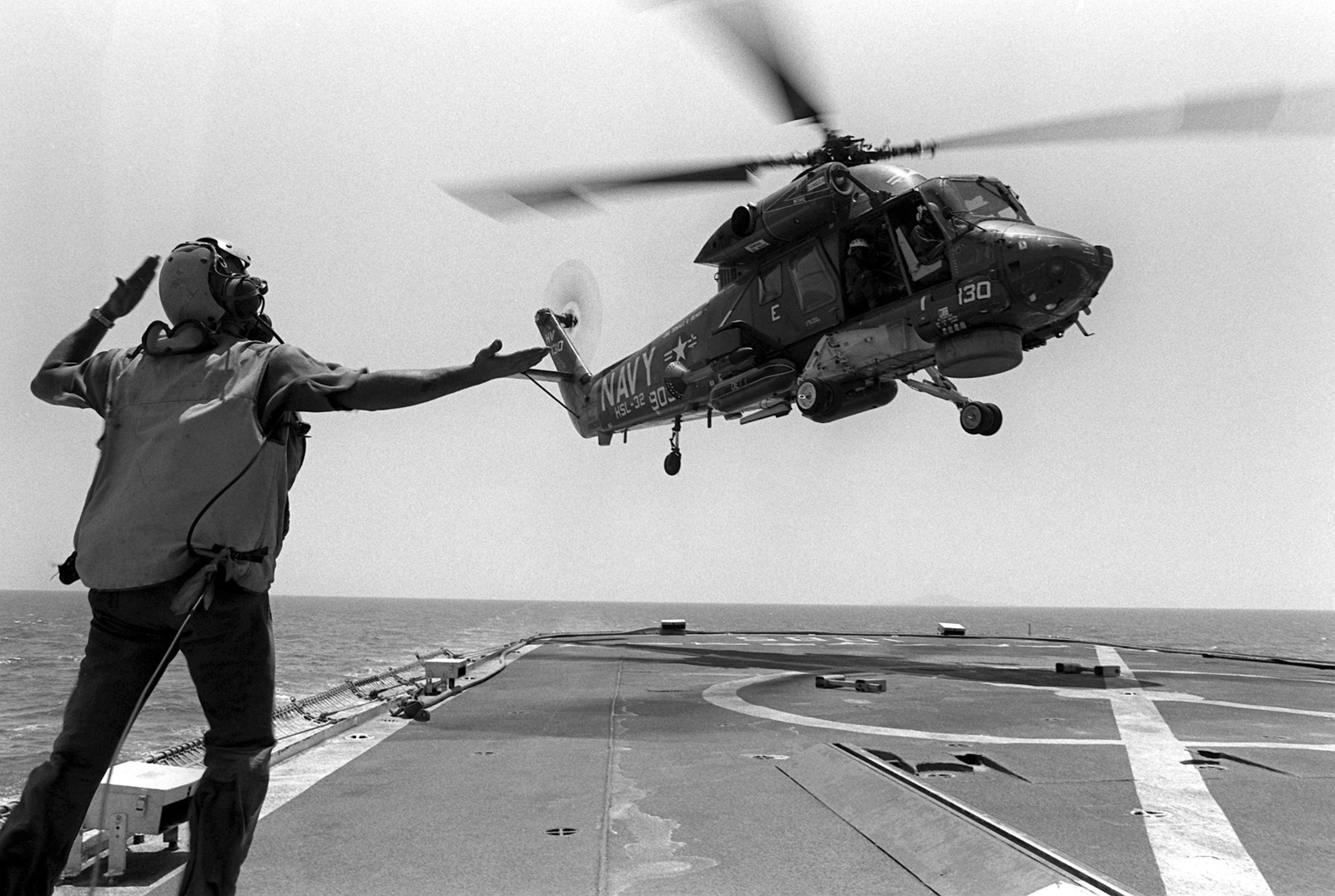 A flight deck crewman directs the pilot of an SH-2 Seasprite helicopter ...