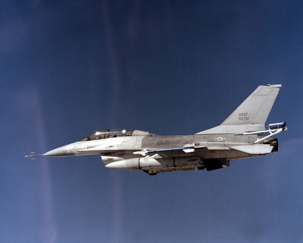 An air-to-air left side view of an F-16B Fighting Falcon aircraft with ...