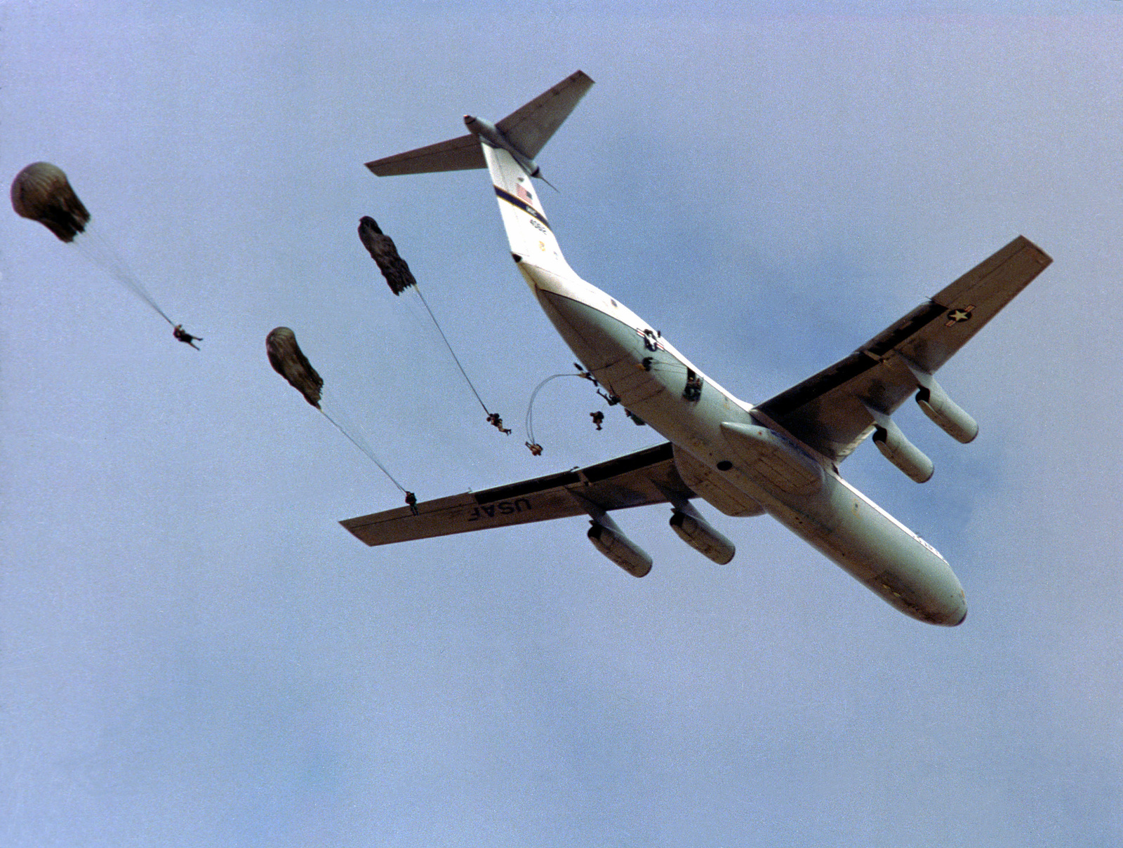 Загрузить изображение Вид снизу самолета C-141 Starlie, сбрасывающего личны...