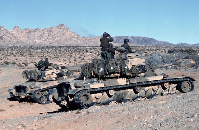 Commanders of two M60A1 tanks stop and check the terrain during ...