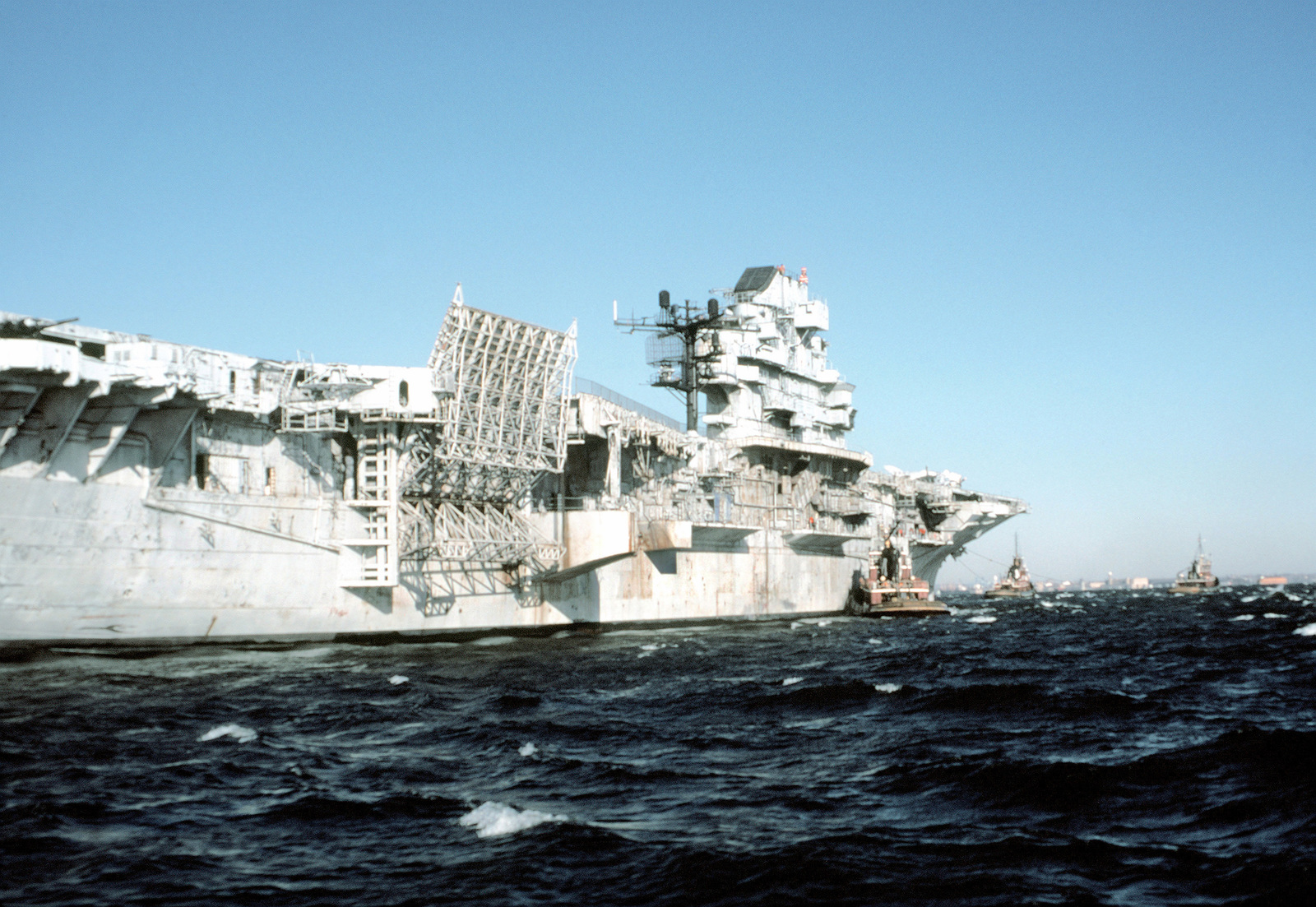 A Starboard Quarter View Of The Aircraft Carrier Ex-Uss Intrepid (Cvs-11)  Under Tow. The Ship Is Approaching The Verrazano-Narrows Bridge En Route To  Bayonne, N.j., To Be Refitted And Opened To The