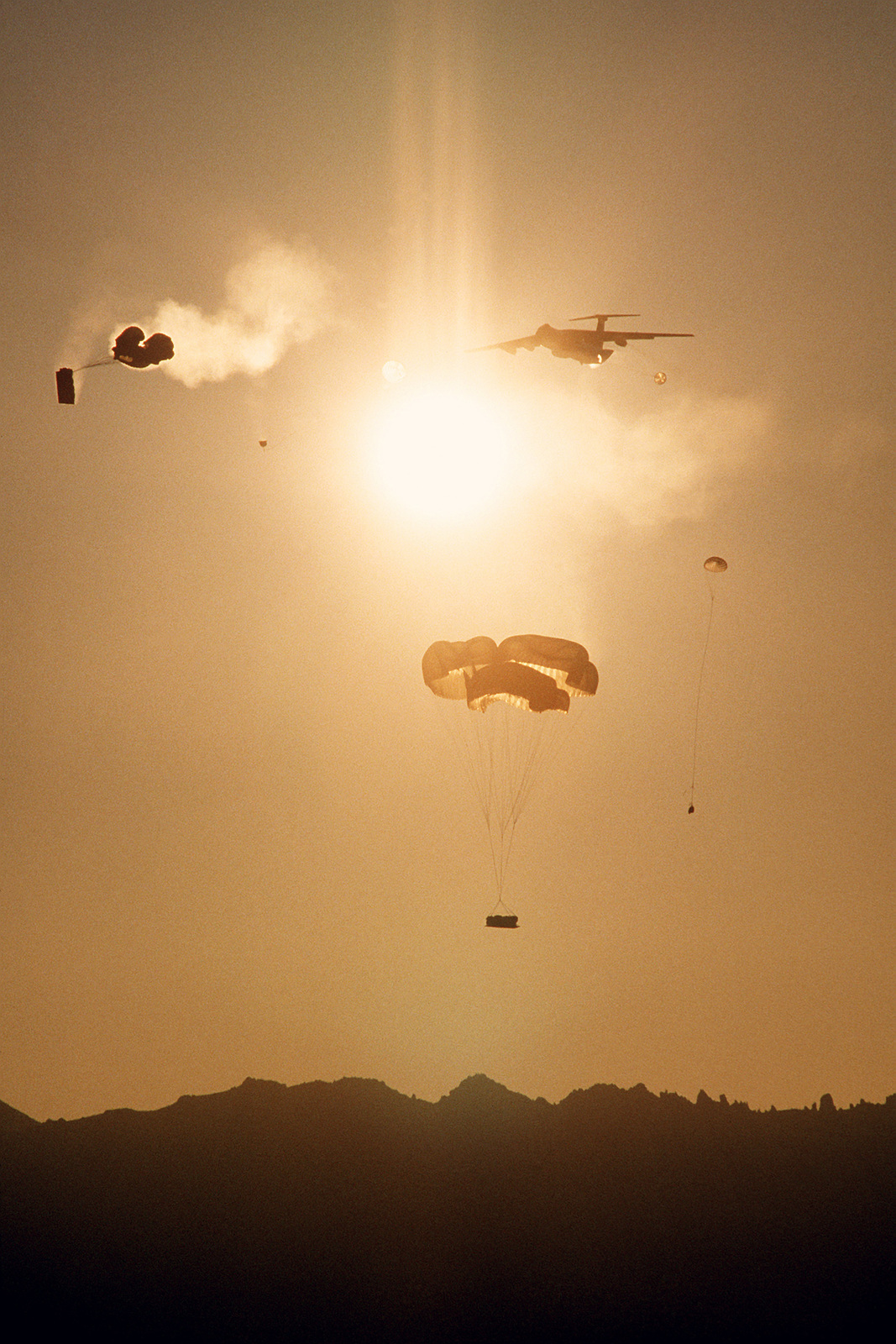 Cargo is dropped from a C-141 Starlifter aircraft over Landing Zone ...