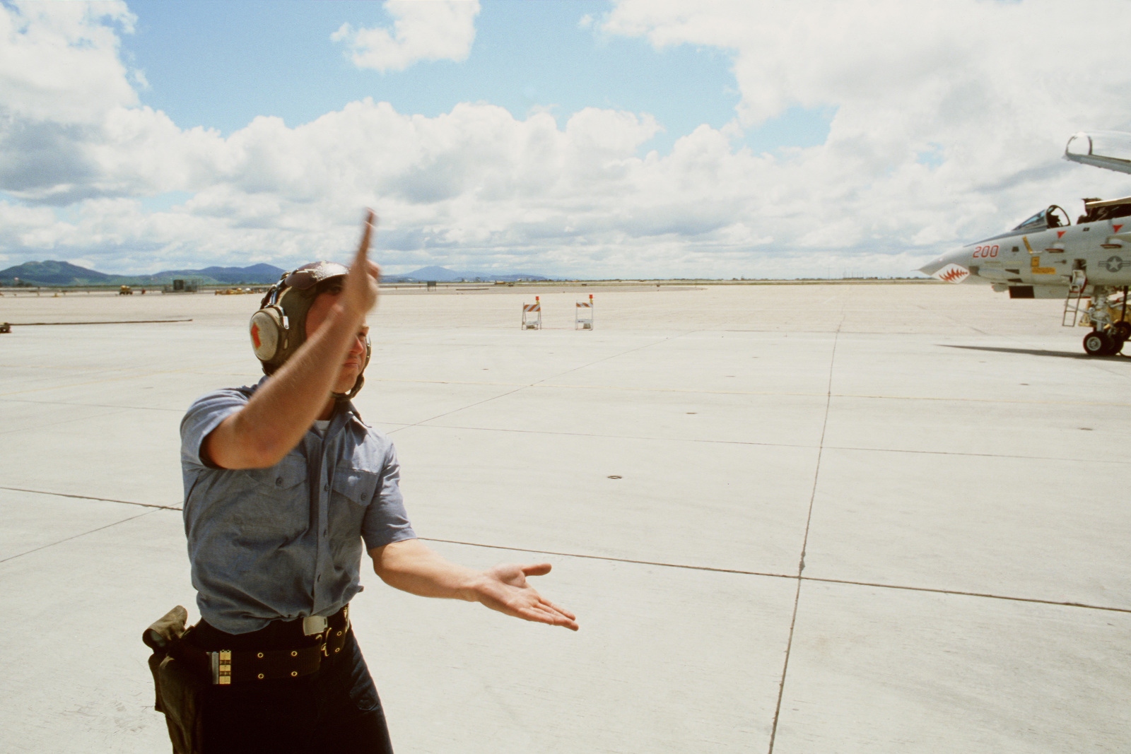 a-ground-crewman-signals-an-f-14-tomcat-aircraft-pilot-as-he-conducts-a