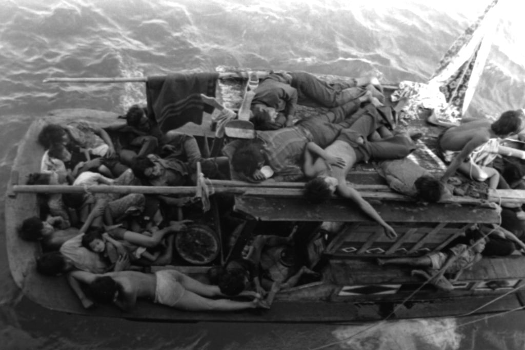 Vietnamese refugees rest in their boat, as the guided missile cruiser ...