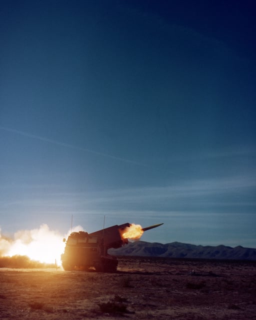 A view of a Multiple Launch Rocket System (MLRS) firing a round of ...