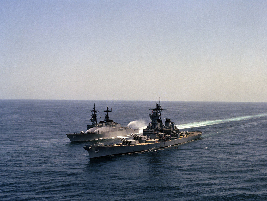 Aerial port bow view of the battleship USS NEW JERSEY (BB 62) underway with  the destroyer USS FIFE (DD 991) to starboard. The crew of the FIFE is  involved in a wash