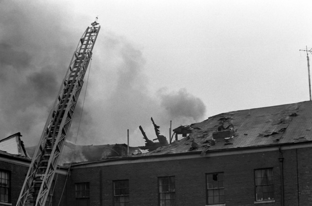 A Ladder On A Hook And Ladder Truck Is Extended Above The Gutted Roof ...