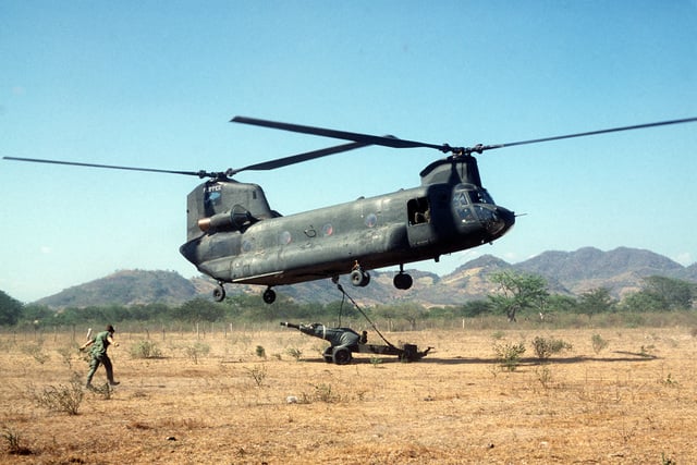 A CH-47 Chinook helicopter lifts an M102 105 mm howitzer off the ground ...