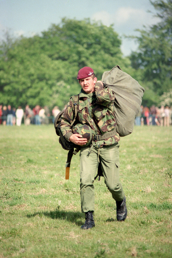 A British paratrooper carries his gear off the landing zone after a  re-enactment of a World War II parachute jump on the 40th anniversary of  D-day, the invasion of Europe - PICRYL 