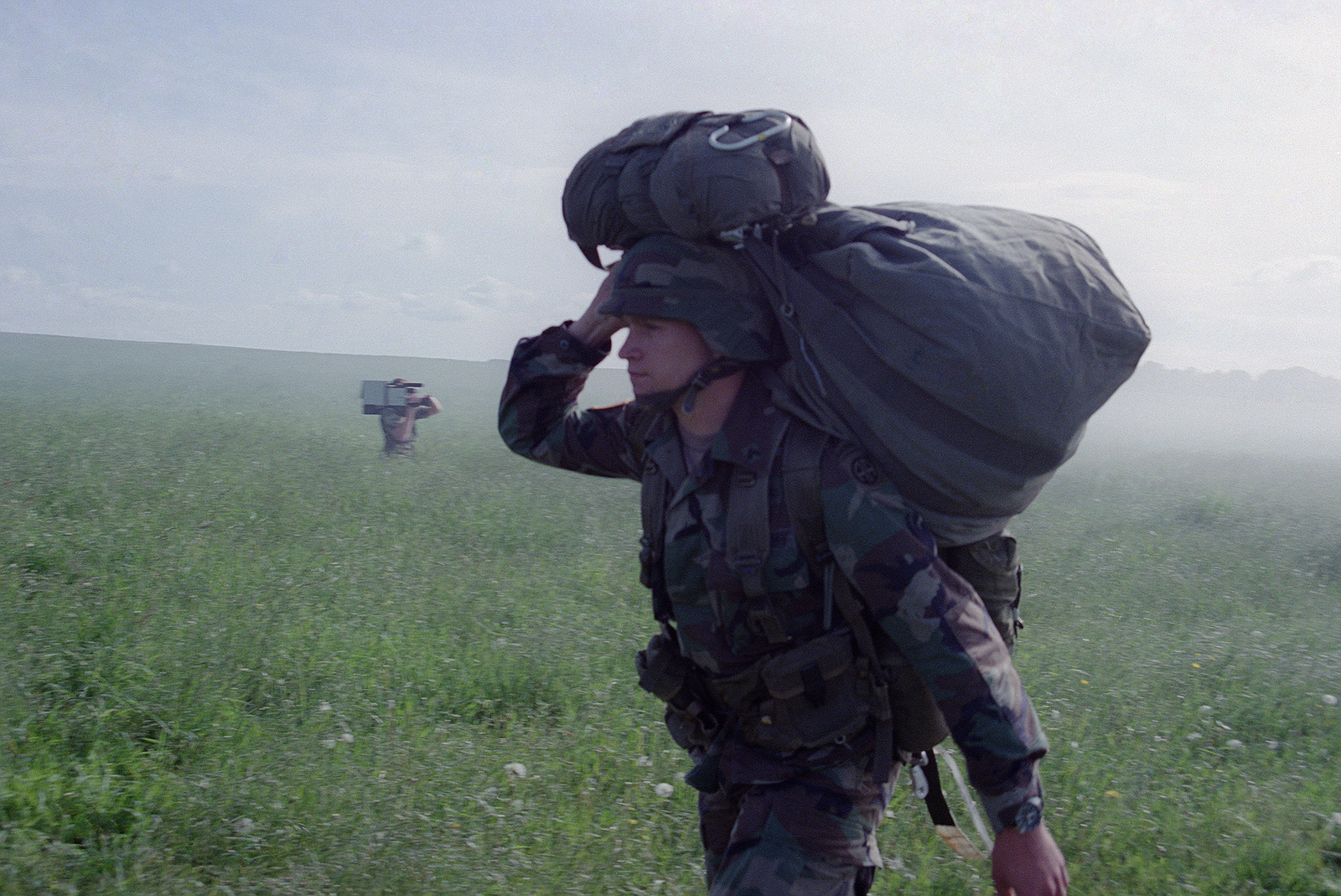 A paratrooper of the 82nd Airborne Division carries his parachute after ...