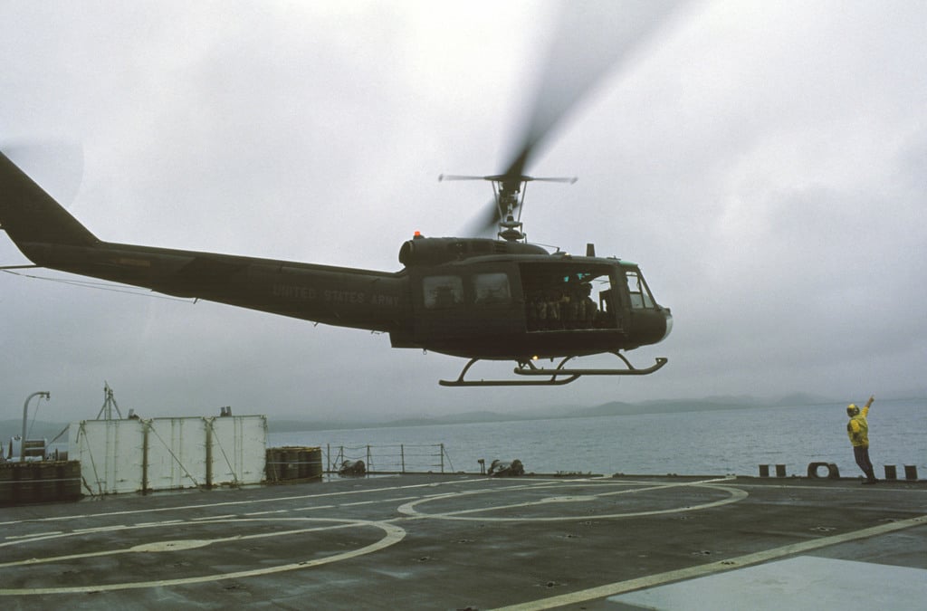 An Army UH-1 Iroquois helicopter lifts off from the deck of the tank ...