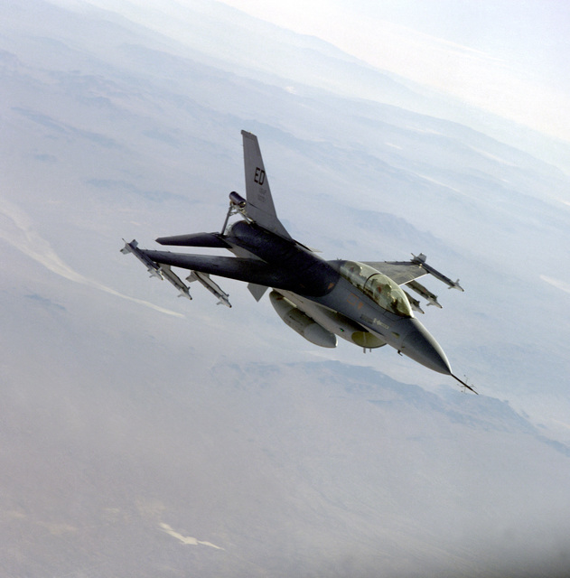 An air to air left side view of an F-16 Fighting Falcon aircraft armed ...