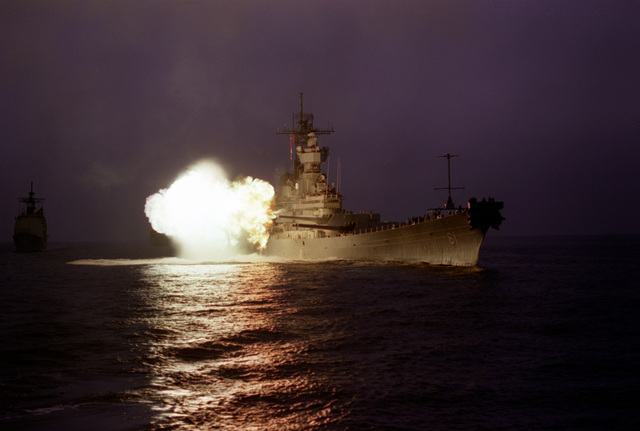 A starboard bow view of the battleship USS IOWA (BB-61) firing a ...