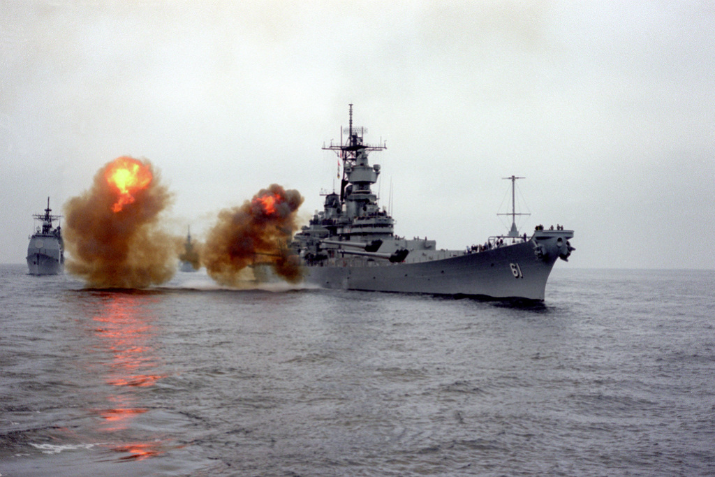 A starboard bow view of the battleship USS IOWA (BB-61) firing a ...