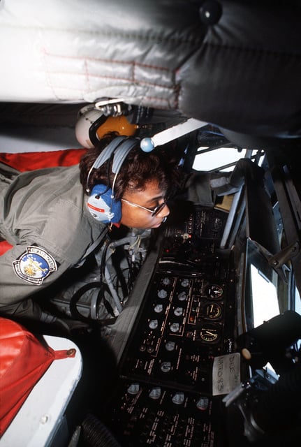 An aerial refueling boom operator looks out the observation window of a ...