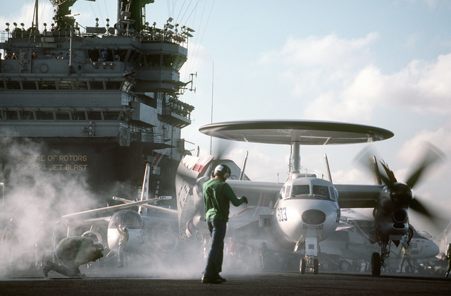 A Catapult And Arresting Gear Crewman Signals To An E C Hawkeye Aircraft Preparing To Be