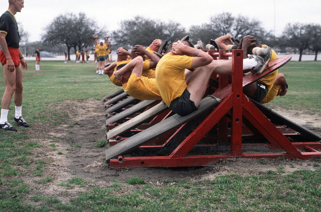 Drill instructor students perform sit ups during physical training