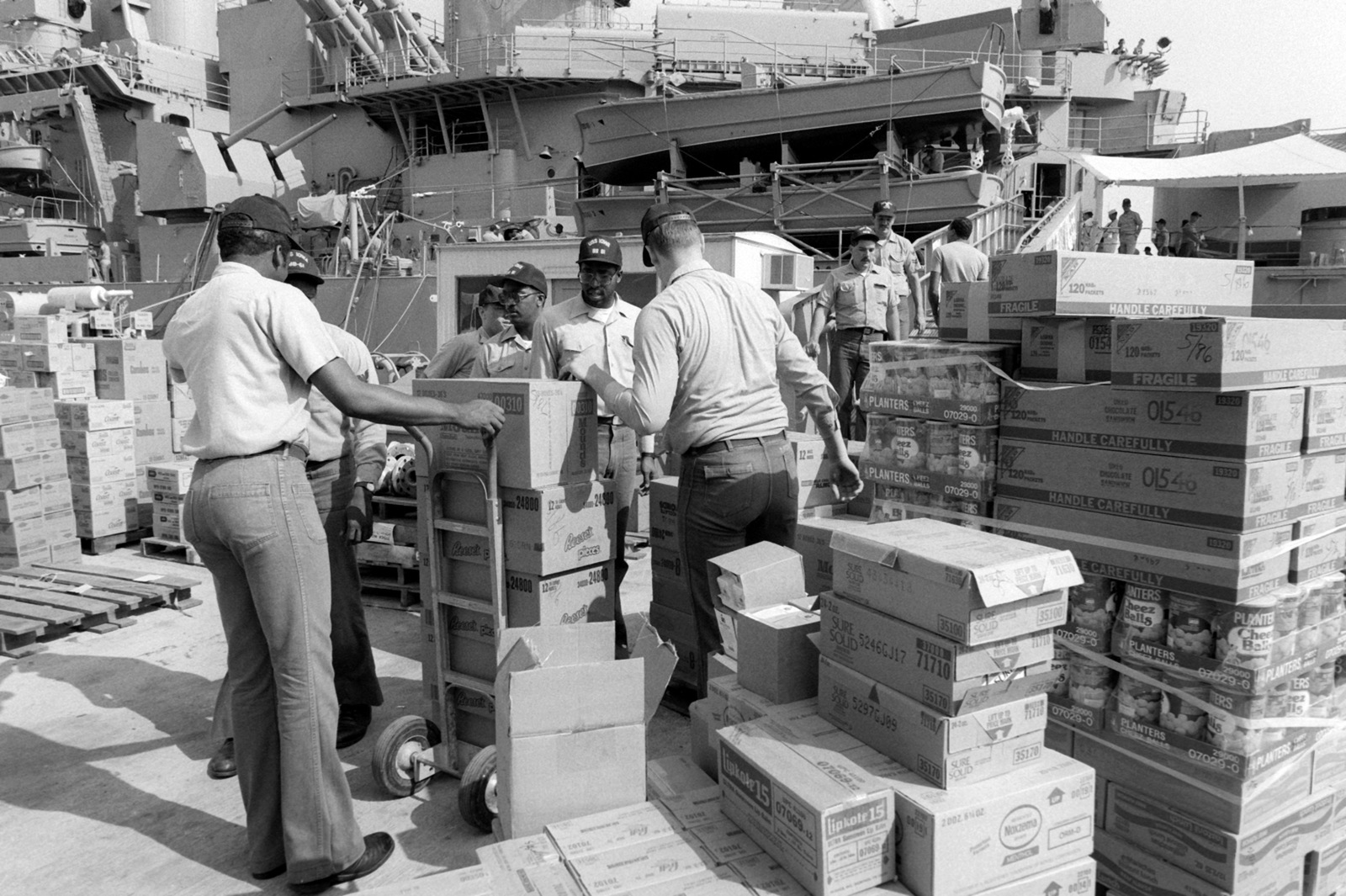 Crew Members Load Cargo Aboard The Battleship USS IOWA (BB 61) Moored ...