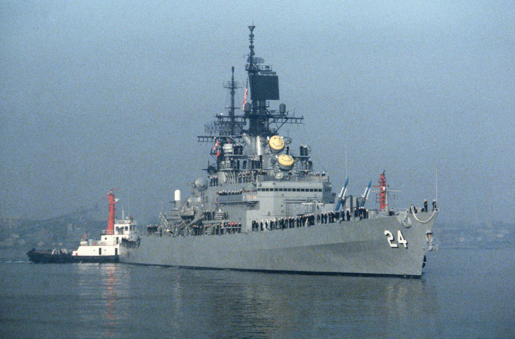 A tug assists the guided missile cruiser USS REEVES (CG 24) into