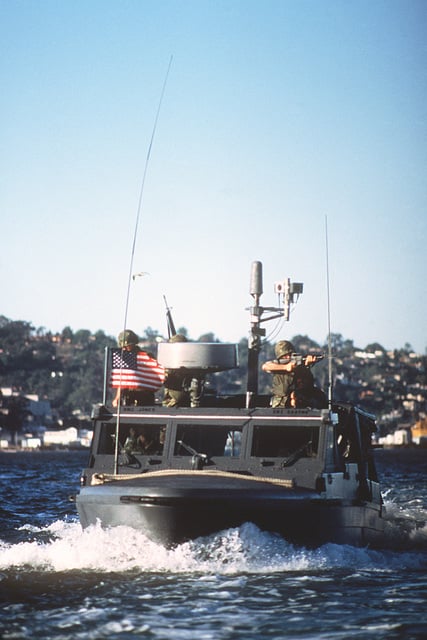 A Sea-Air-Land (SEAL) team member aims his rifle while other SEALs ...