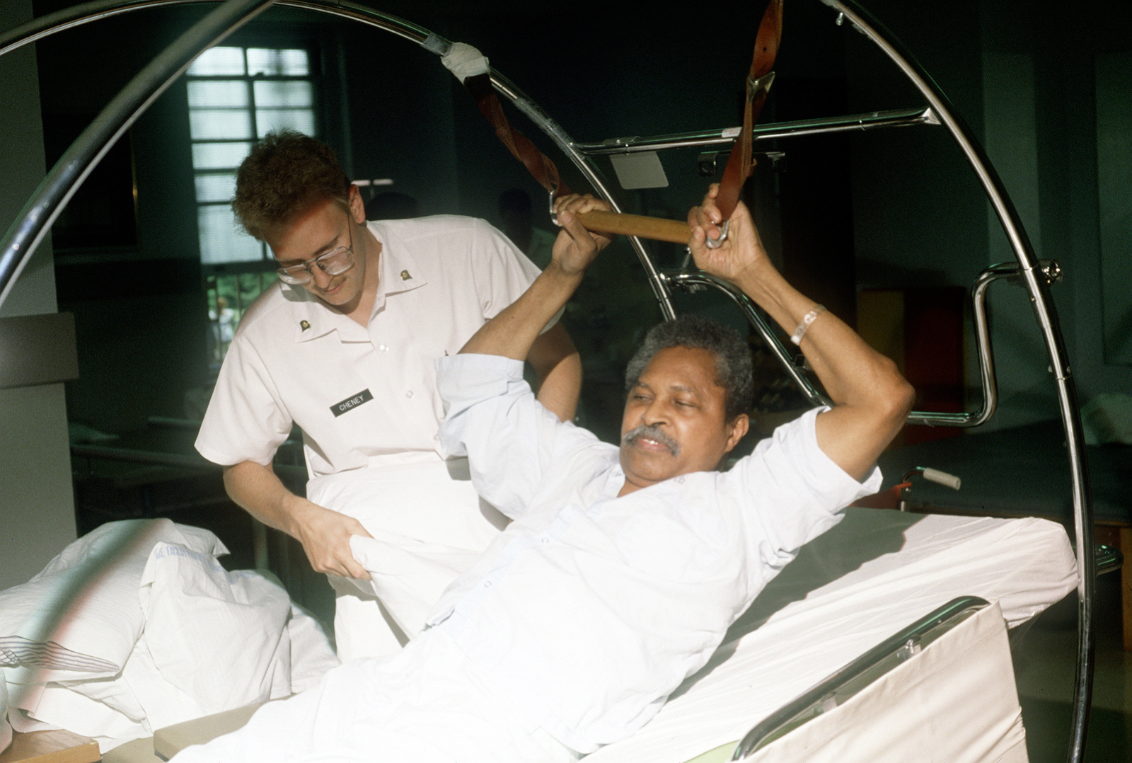 A therapist helps a patient exercise his arms and legs during physical