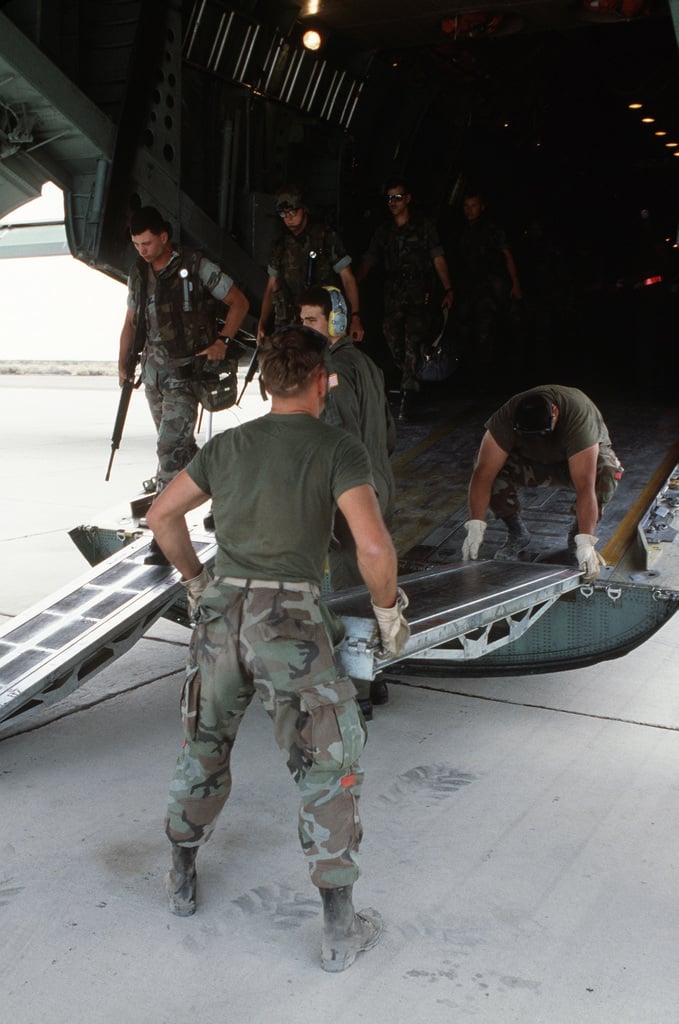 Air Force ground crewmen assemble a boarding ramp as Marines march out ...