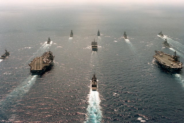 An Aerial View Of Various Ships Underway In Formation. They Are 