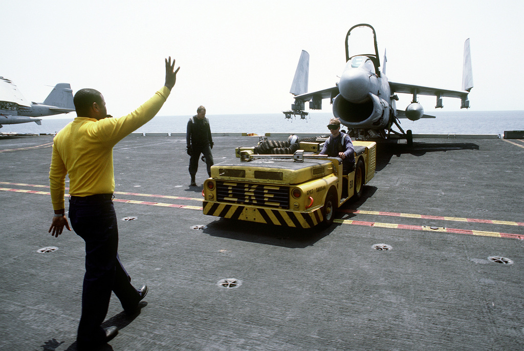 A Plane Director Supervises The Towing Of An A 7e Corsair Ii Aircraft By An Md 3a Tow Tractor 