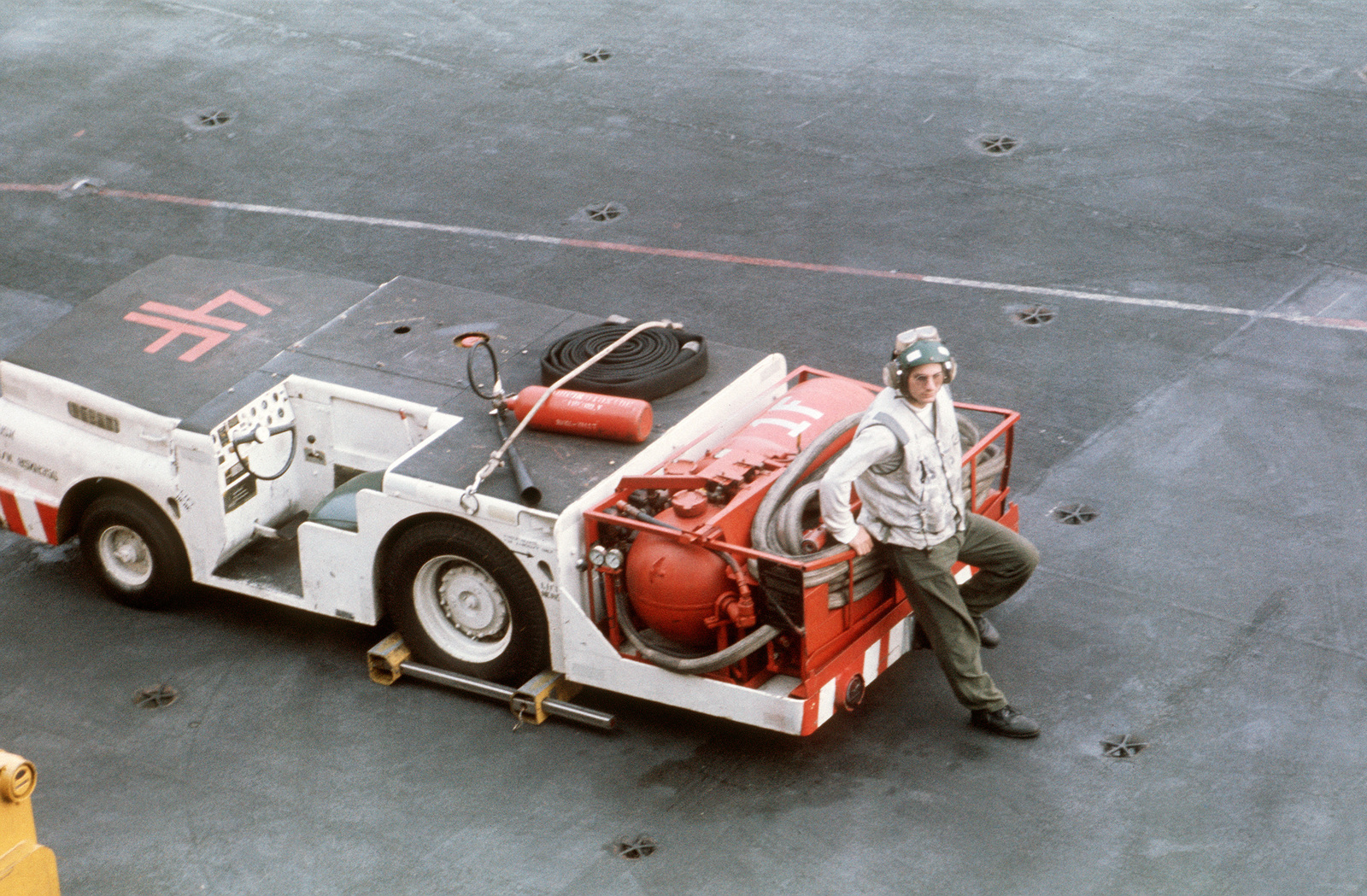 A Crewman Stands By With An MD-3A Tow Tractor Converted For Fire ...