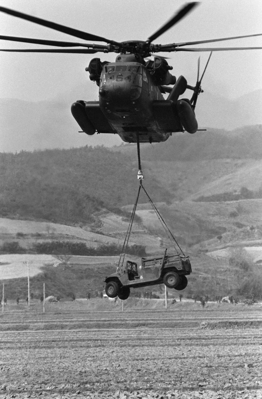 A CH-53E Super Stallion helicopter lifts an M998 multi-purpose wheeled ...