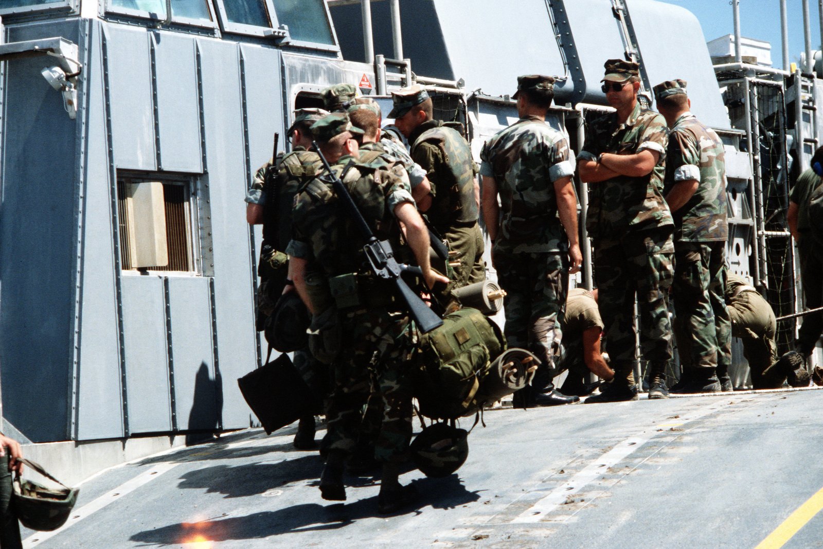 Marines carry their gear up the ramp of an air cushion landing craft ...