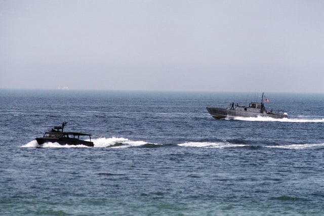 A PB Mark III patrol boat guards a Seafox SEAL craft as it heads toward ...