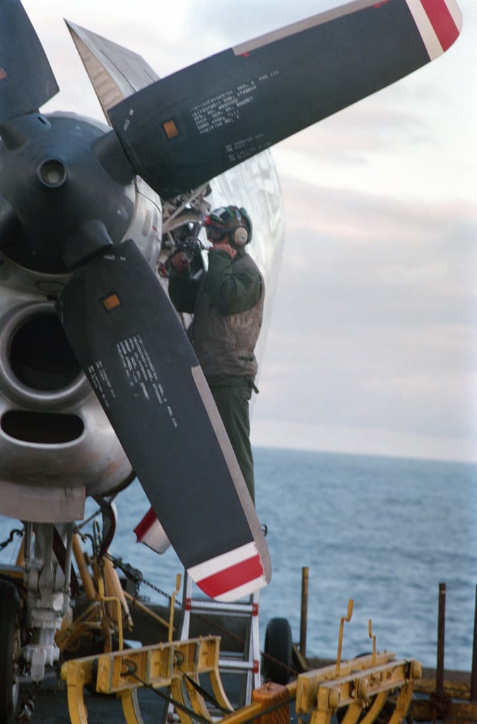 A Flight Deck Crewman Services An E C Hawkeye Aircraft Aboard The