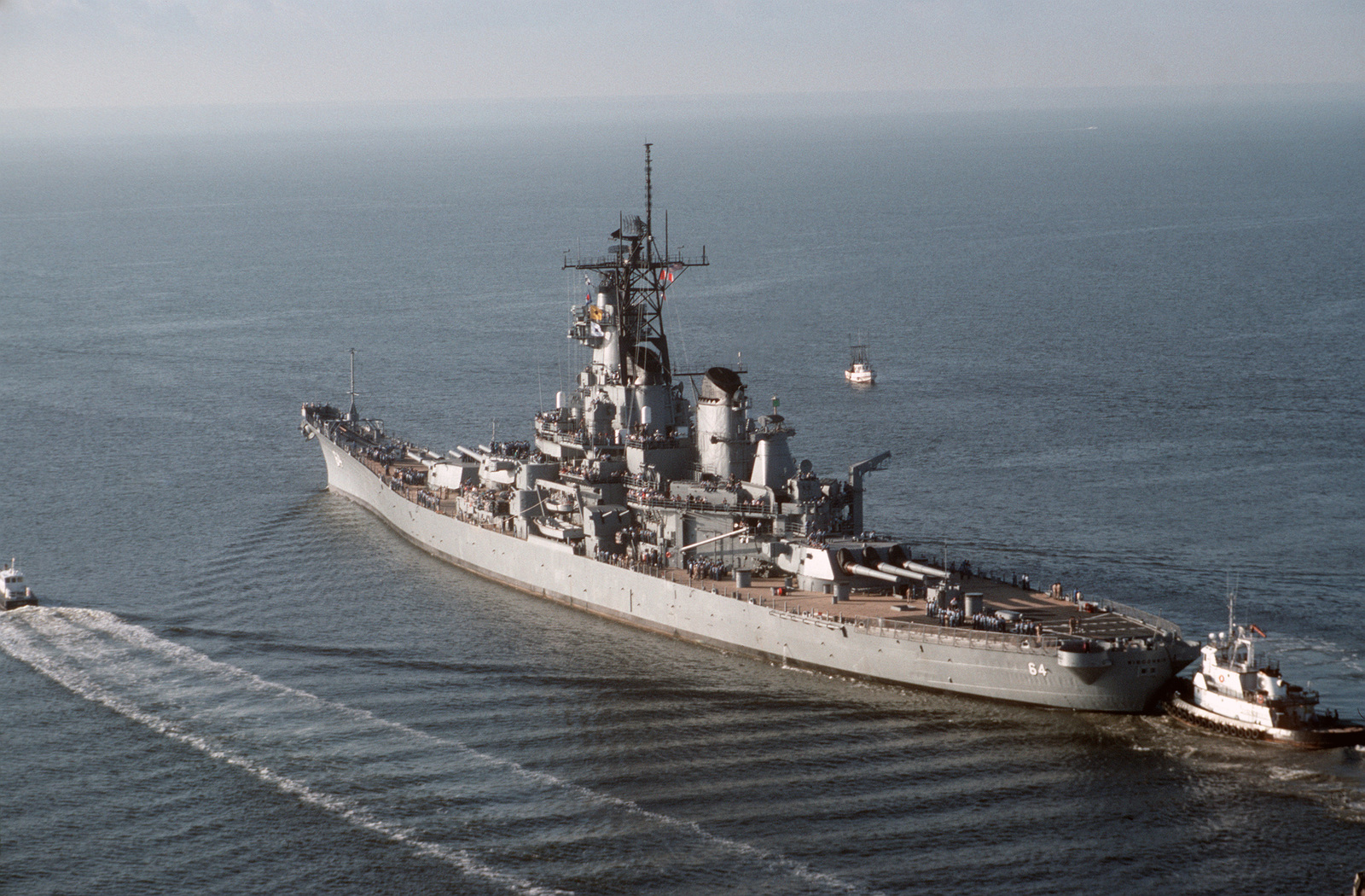 Tug boats assist the battleship USS WISCONSIN (BB 64) out to sea prior ...