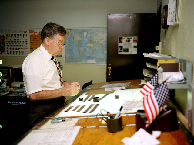 a-civilian-employee-inspects-negatives-on-a-light-table-at-the-station