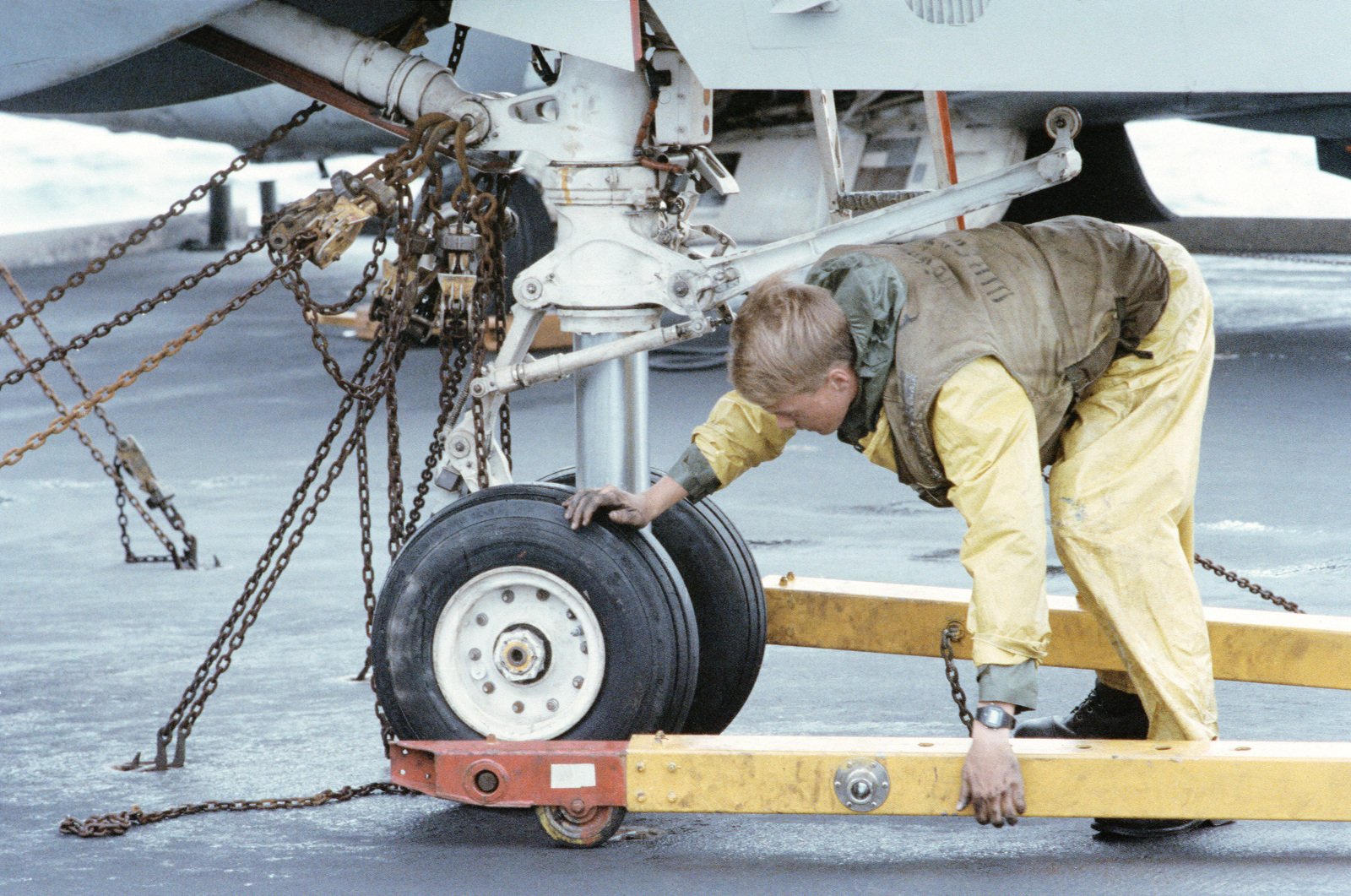 A Flight Deck Crewman Attaches A Towbar To The Nose Wheel Of An