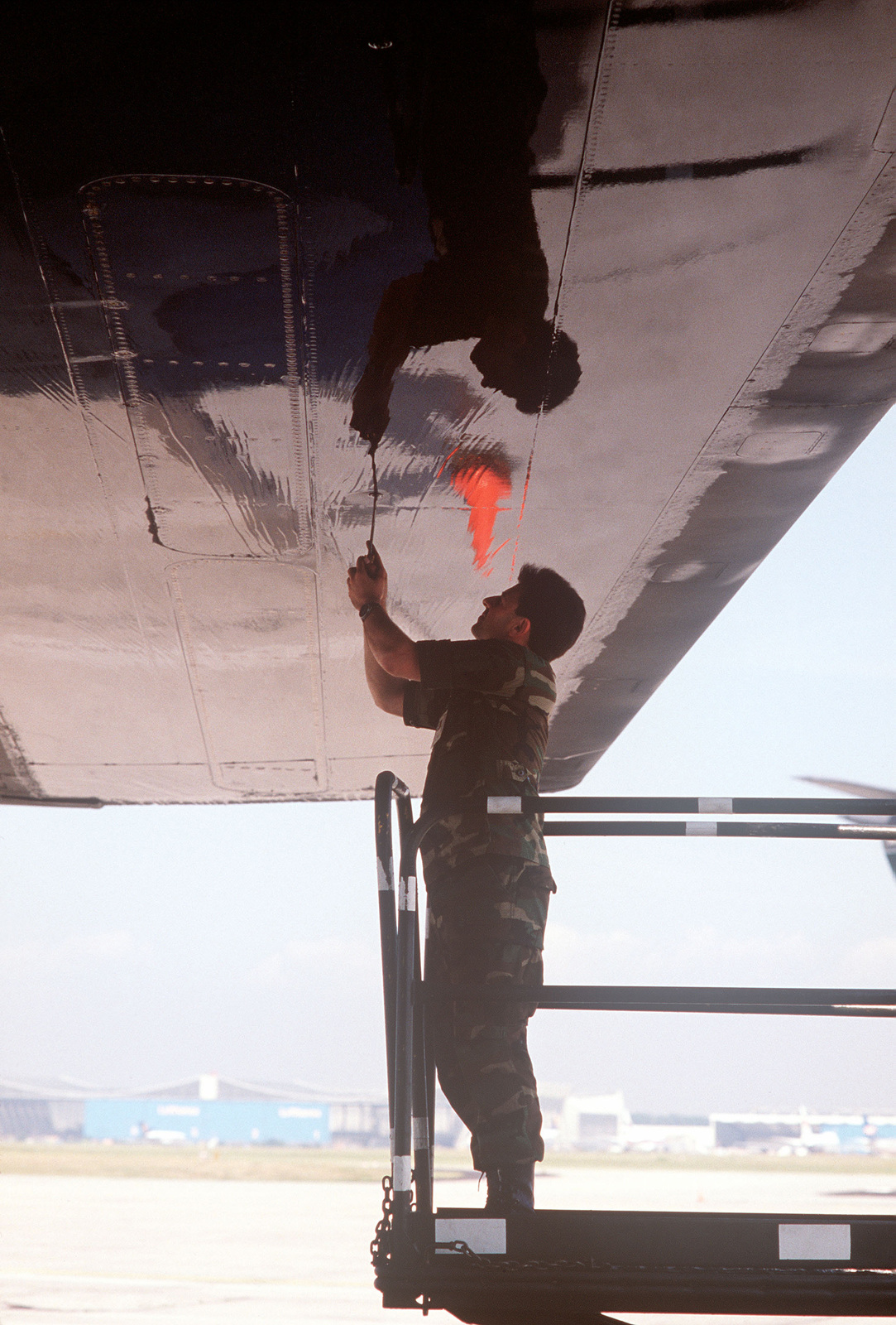 A flight line support technician works under the wing of an aircraft ...