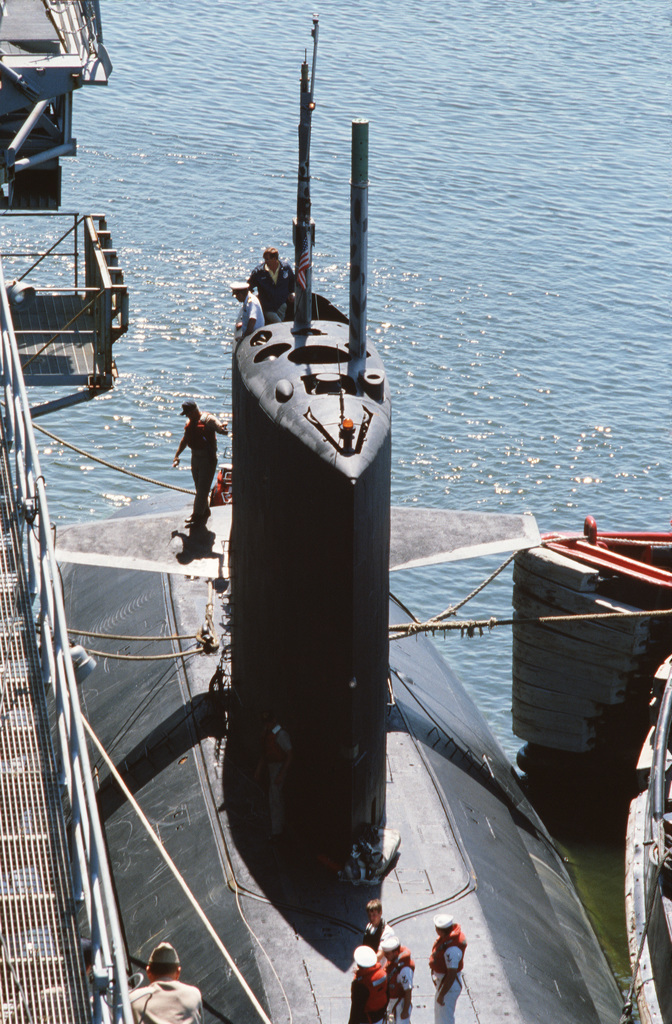 An officer monitors mooring operations from the sail of the damaged ...