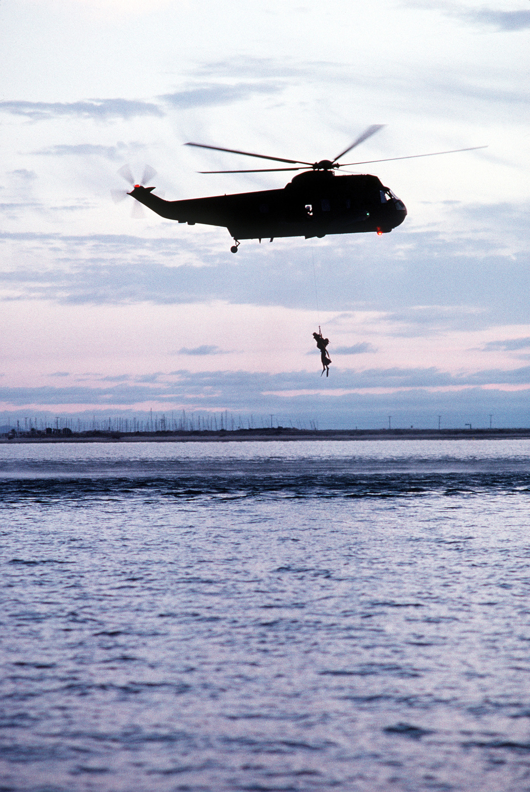 The late afternoon sky silhouettes an SH-3H Sea King helicopter from ...