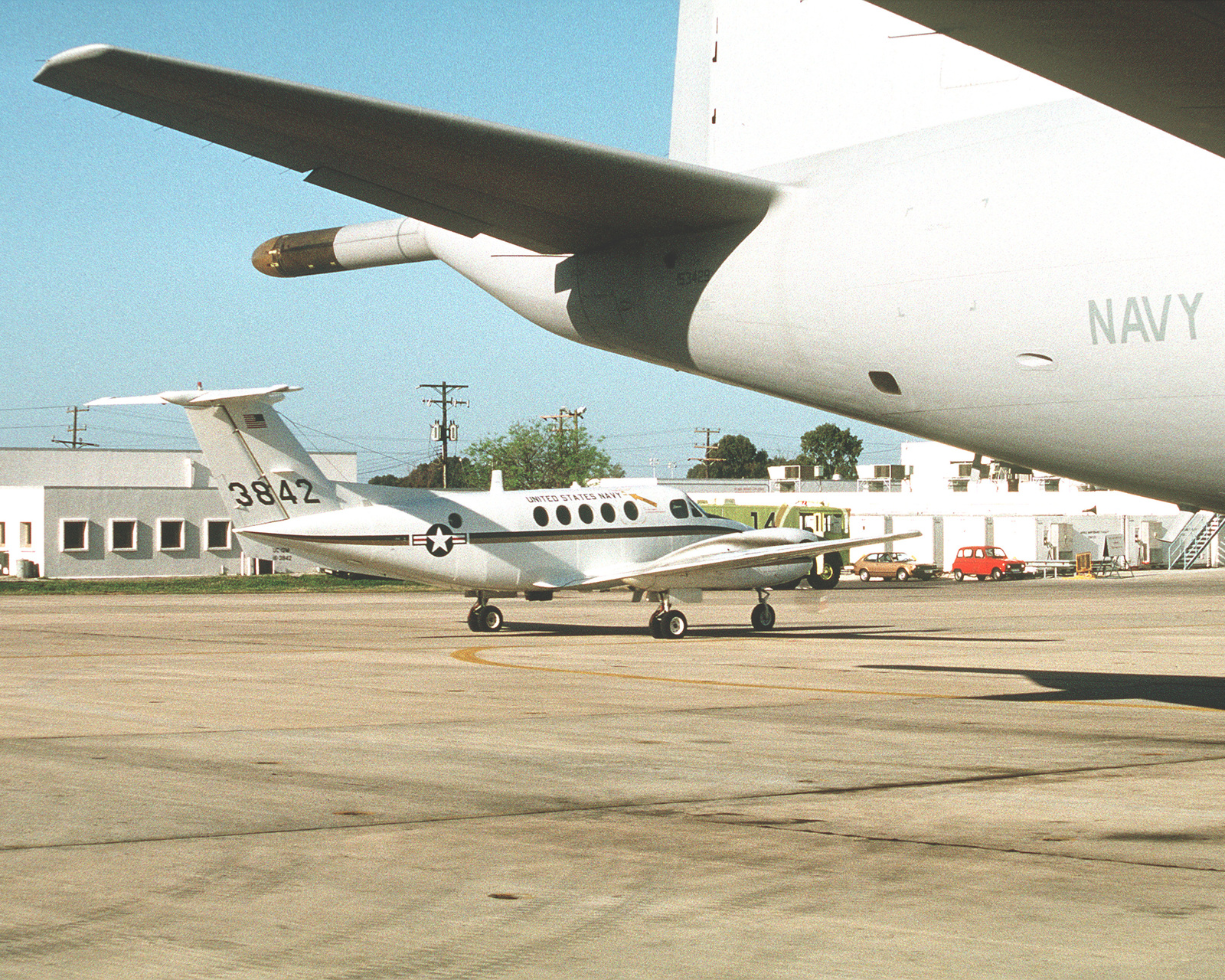 A Uc-12 Huron Aircraft Sits On The Flight Line, In The Shadow Of The Tail  Section Of A P-3 Orion Aircraft. Exact Date Shot Unknown - Nara & Dvids  Public Domain Archive