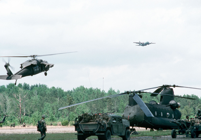 An Army UH-60 Black Hawk helicopter comes in to land beside a CH-47 ...