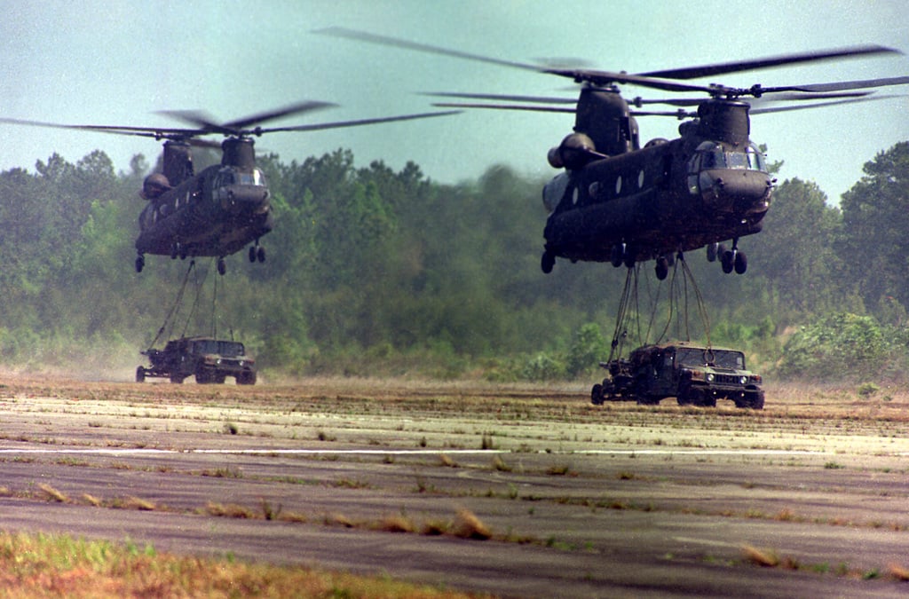 Two Army CH-47 helicopters hover as they prepare to make an external ...