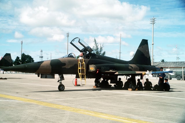 Thai ground crewmen sit in the shade beneath a Royal Thai Air Force F ...