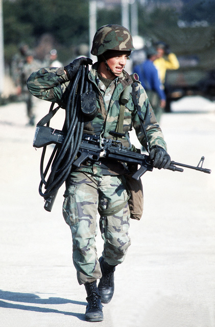 A Marine armed with an M-60E3 7.62mm machine gun carries an electrical ...