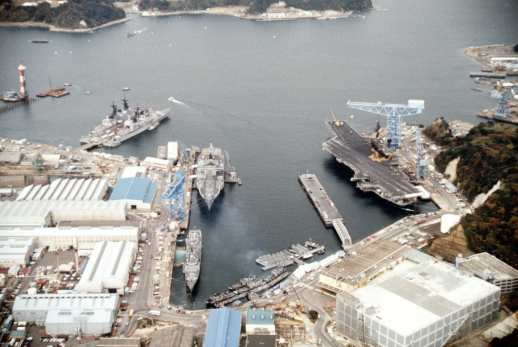 An aerial view of docked warships. Right to left: the aircraft carrier ...