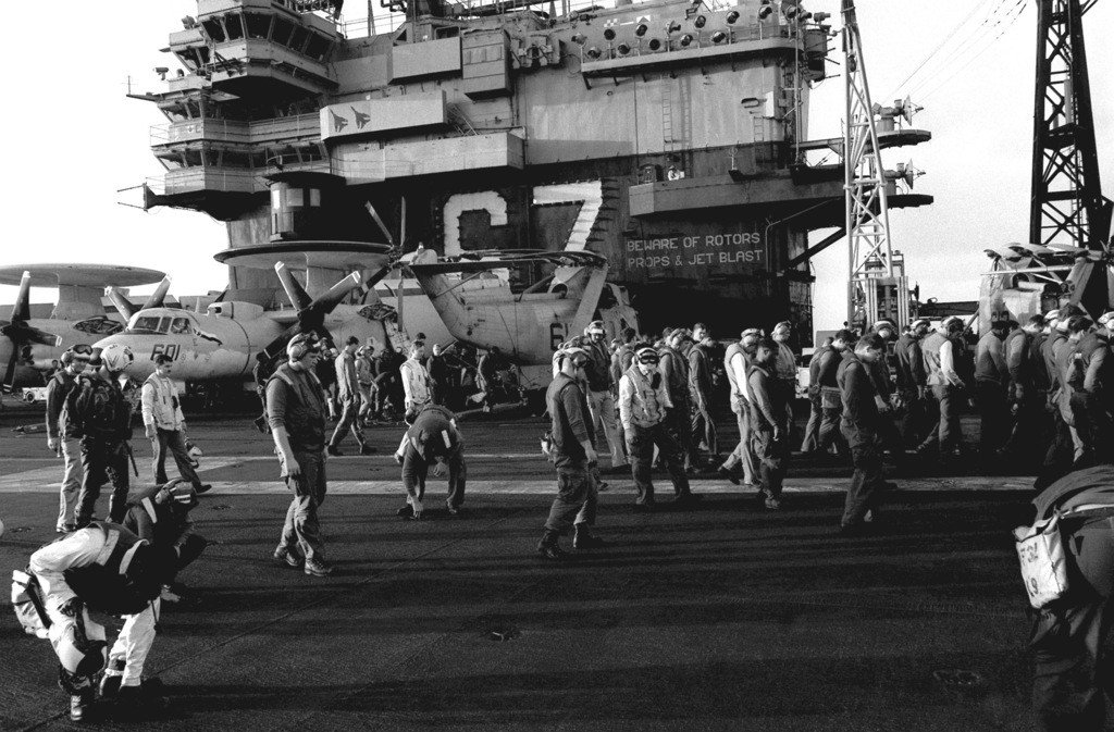 Dozens Of Crewmen Walk Slowly Along The Flight Deck Of The Aircraft Carrier Uss John F Kennedy 