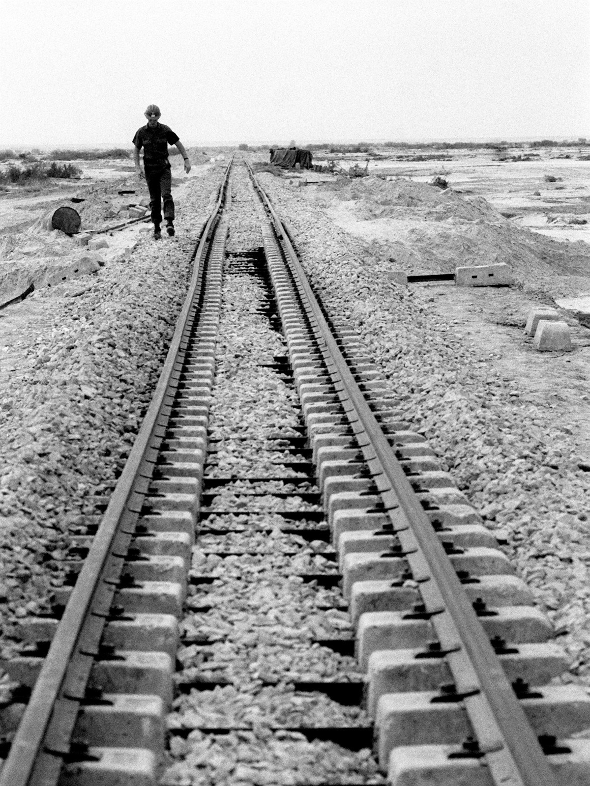 A US Navy Seabee walks along a flood-damaged railroad during exercise ...